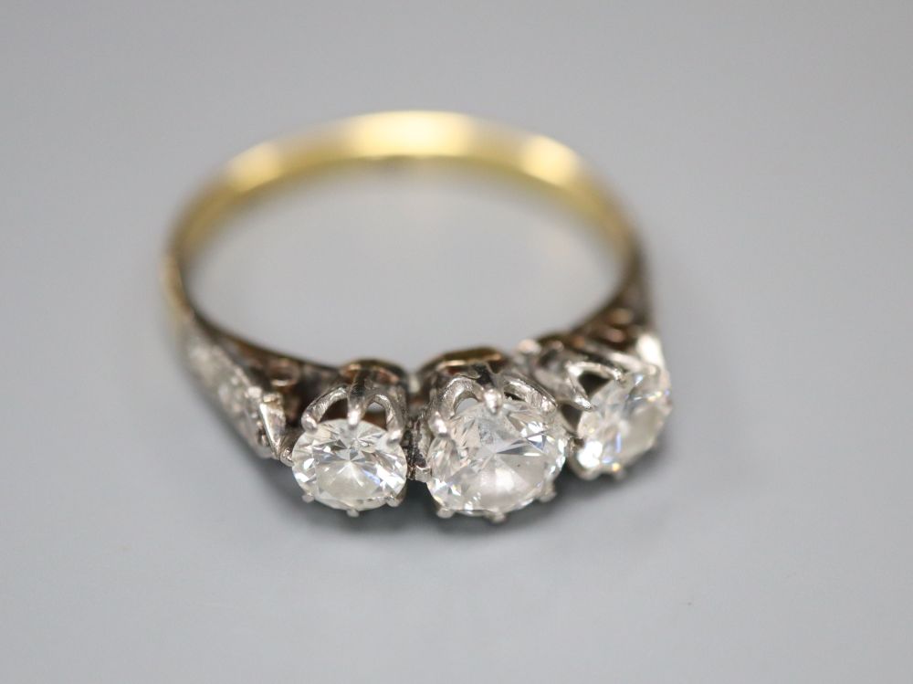 A mid 20th century 18ct and plat three stone diamond ring, with diamond set shoulders, size K/L, gross 2.4 grams.